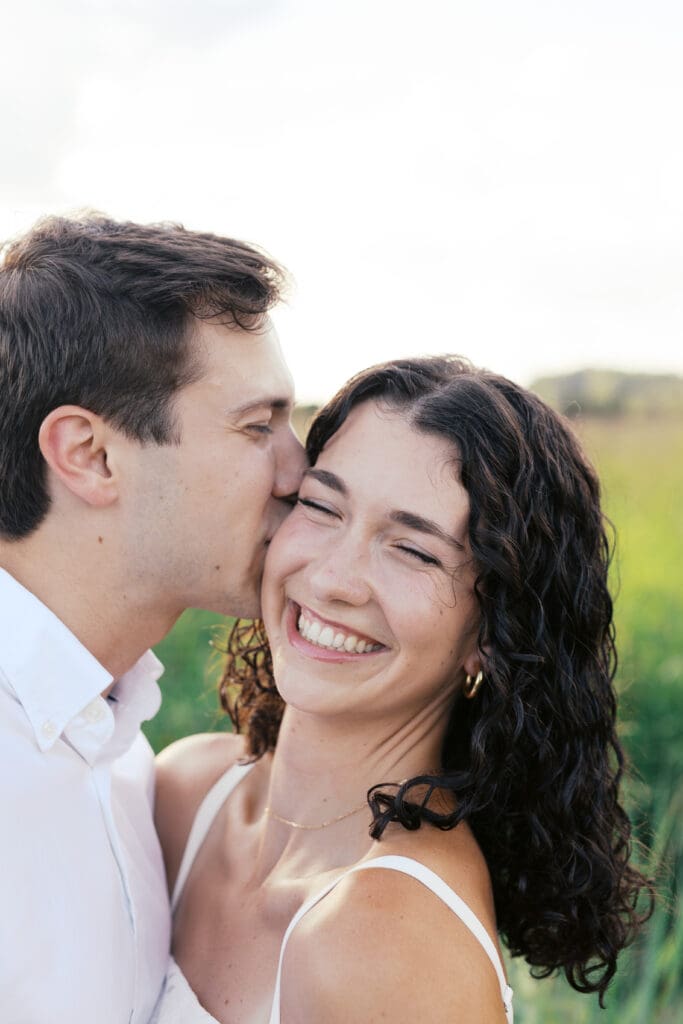 Groom kissing brides cheek during engagement session in East Tennessee mountains