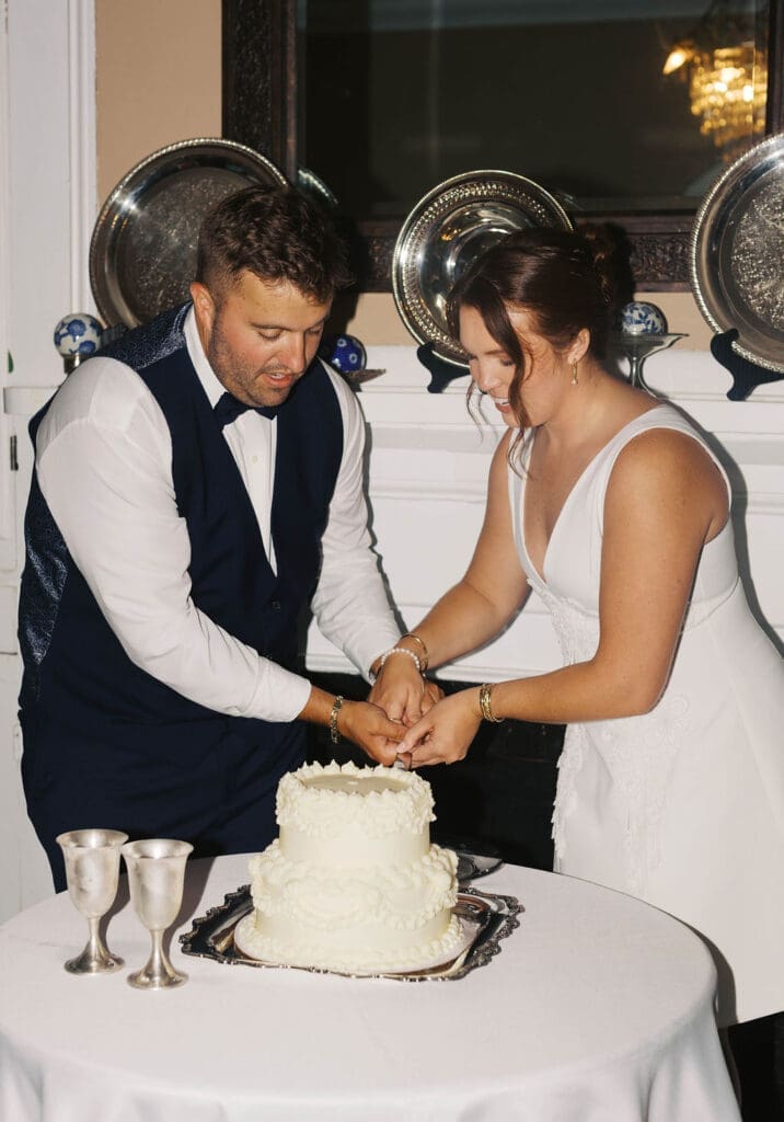 flash photo of bride and groom cutting their cake with bog smiles
