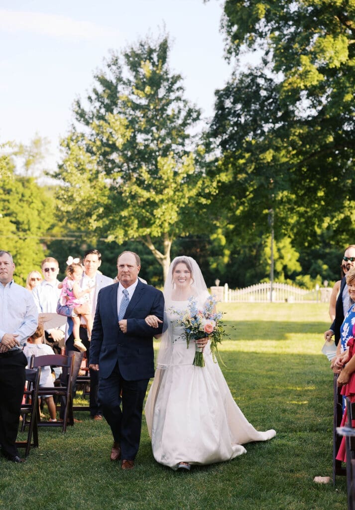 joyful bride and dad walking down aisle together 